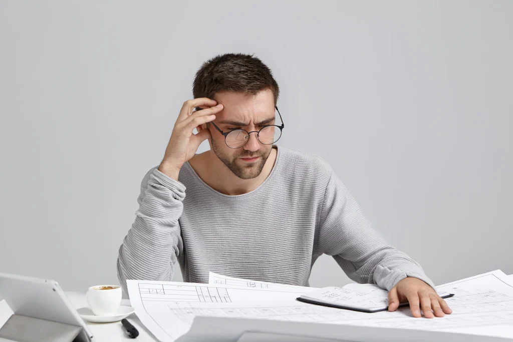 The Real Reason ADHD Brains Struggle With Boring Tasks (It's Your Synapses, Not Laziness) 1 puzzled man working on blueprints at desk 2026 03 26 05 32 13 utc